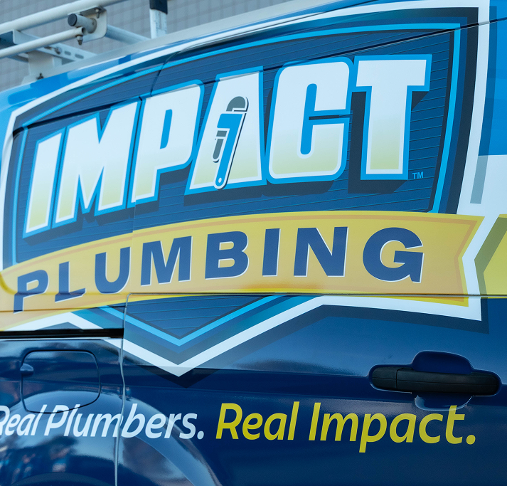 A van with a large logo reading “IMPACT PLUMBING” and the slogan “Real Plumbers. Real Impact.” in blue, yellow, and white lettering on the side promotes trusted Plumbing Services in Las Vegas NV.